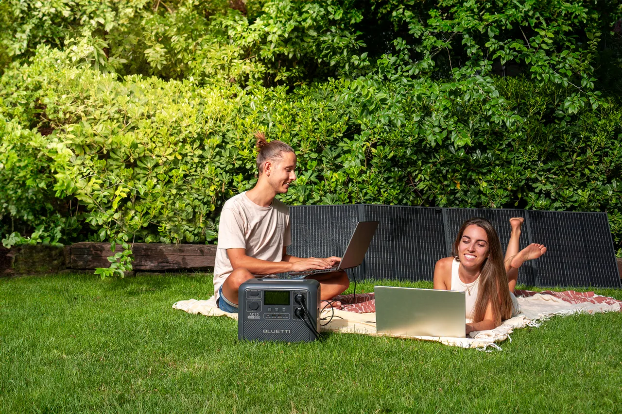 Casal recarregando a BLUETTI AC70 com painel solar ao ar livre